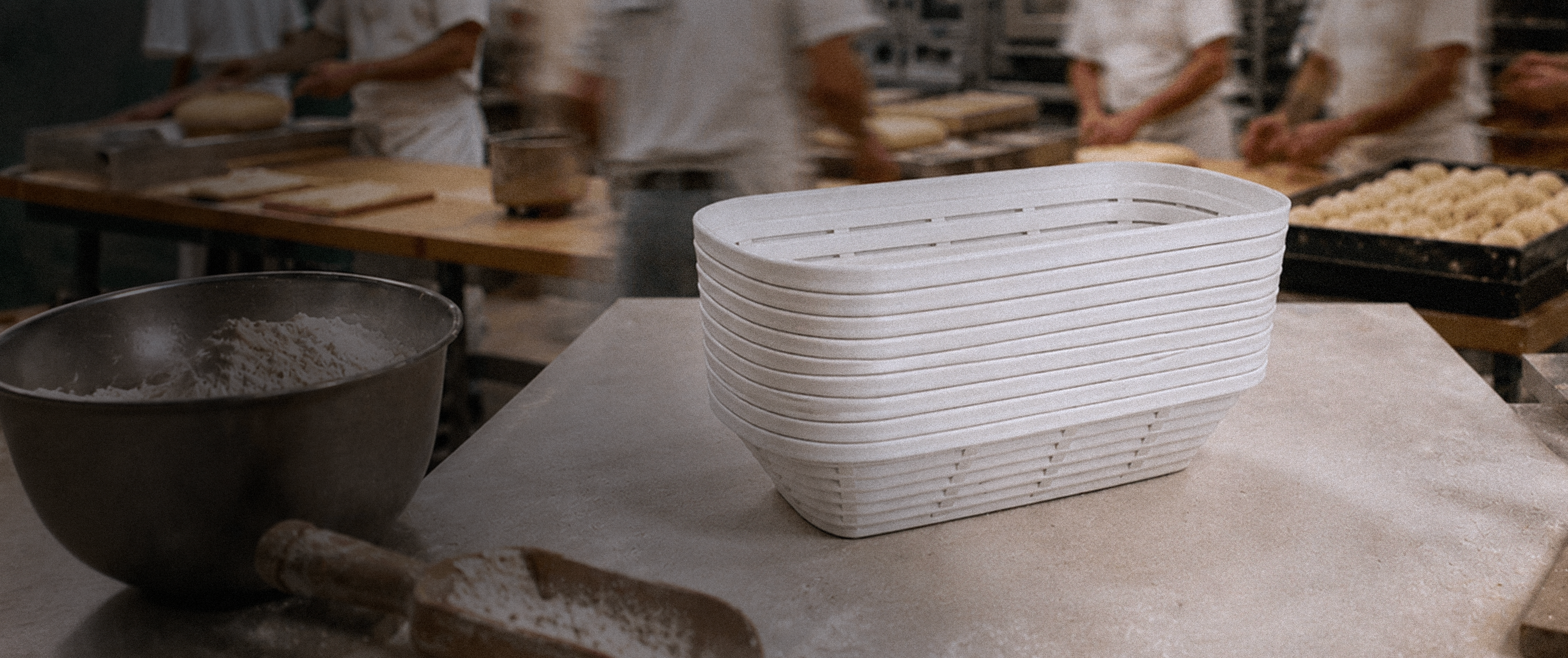 White bread basket on a table with flour and other baking items in a kitchen setting