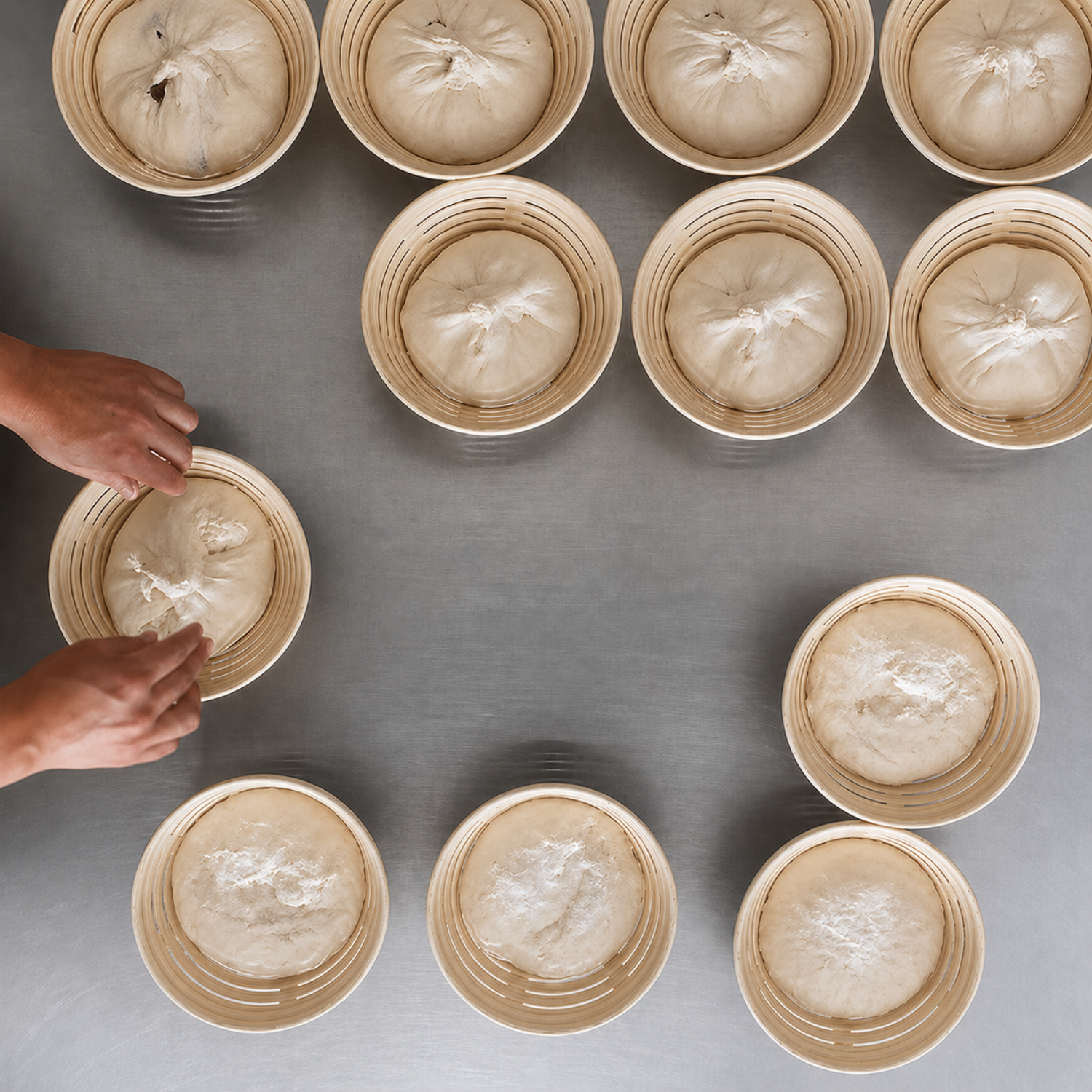 Round bannetons holding sourdough dough during proofing in a professional bakery setup.